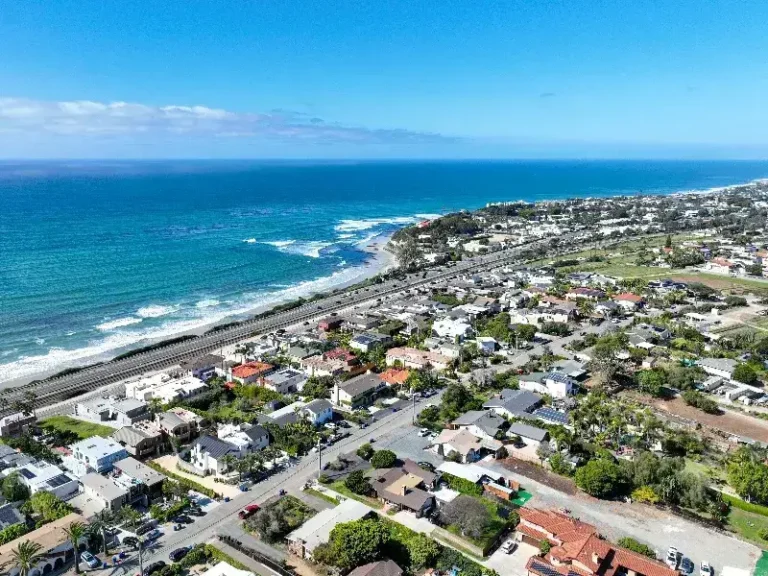 Coastal town with houses near the ocean and a railway line running parallel to the shore.