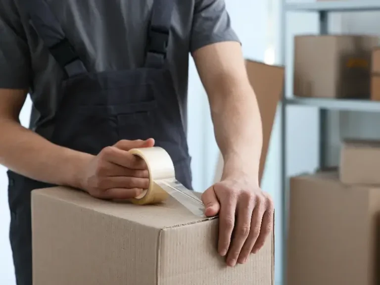 Person sealing a cardboard box with clear packing tape.